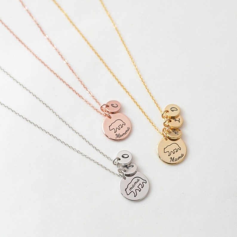 May include: Three silver necklaces with bear pendants. The necklaces have different lengths and feature initial charms. The pendants are engraved with the words "mama", "mommy", and "mama".