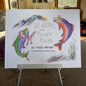 May include: A children's book cover with a colorful illustration of two fish. The title of the book is "Sir Brooks and the hookie hooks" by Russ Hefner, illustrated by Serra Trinh.