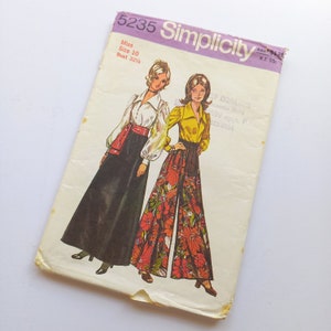 May include: Simplicity sewing pattern number 5235 for a miss size 10 with a bust measurement of 32 1/4 inches. The pattern shows two women wearing different styles of trousers. One woman is wearing a black skirt with a red belt and a white blouse with long sleeves. The other woman is wearing a pair of wide-legged trousers with a floral print and a yellow blouse with long sleeves.