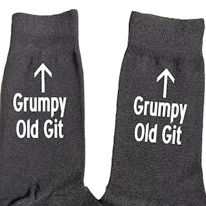 Könnte beinhalten: Ein Paar schwarze Socken mit weißem Text, der auf jeder Socke "Grumpy Old Git" lautet.
