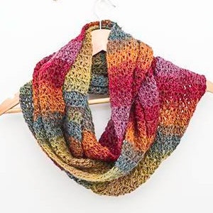 Puede incluir: Una bufanda de ganchillo infinita de colores con un degradado de rojo, naranja, amarillo, verde y azul.