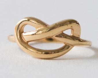 May include: A gold knot ring with a simple, elegant design.