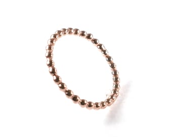 Könnte beinhalten: Ein roségoldener Perlenring. Der Ring besteht aus kleinen, runden Perlen, die miteinander verbunden sind, um einen durchgehenden Kreis zu bilden.