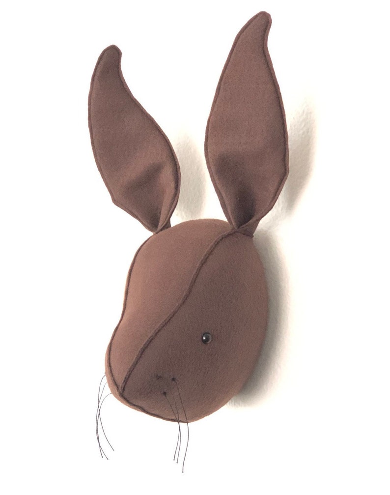 May include: A brown felt rabbit head wall decor with black felt eyes and whiskers.