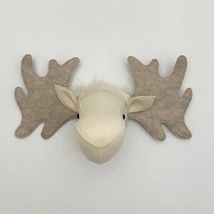 May include: A white felt moose head with brown felt antlers. The moose head is a wall decoration.