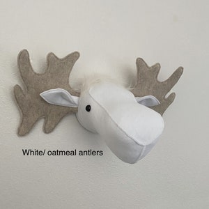 May include: White felt moose head with oatmeal felt antlers. The moose head is a wall decoration.