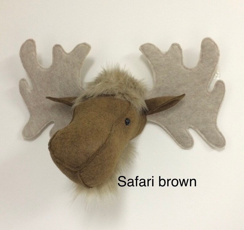 May include: A brown felt moose head with a furry face and large, light brown felt antlers. The text "Safari brown" is printed below the moose head.