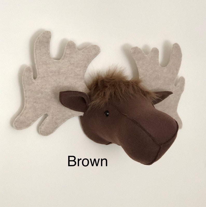 May include: Brown felt moose head wall decor with large, beige felt antlers. The moose head has a furry brown face and black eyes.