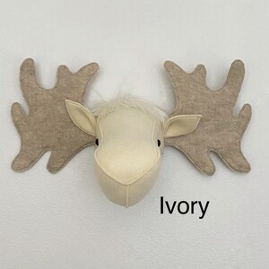 May include: A white felt moose head with large brown felt antlers. The moose head is mounted on a white wall with the word "Ivory" written below it.