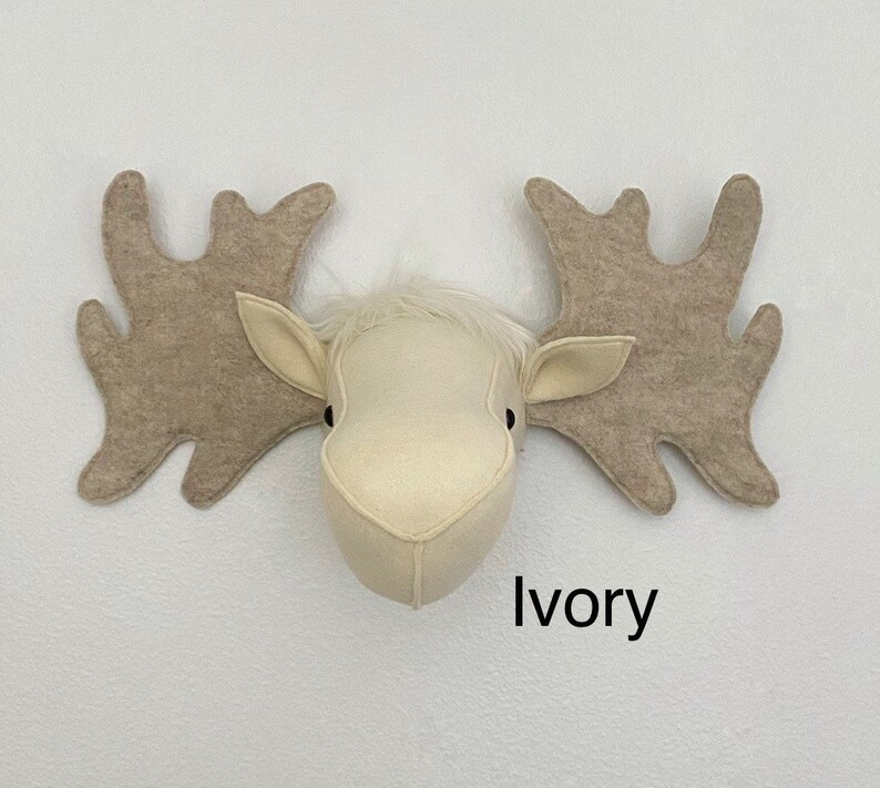 May include: A white felt moose head with large brown felt antlers. The moose head is mounted on a white wall with the word "Ivory" written below it.