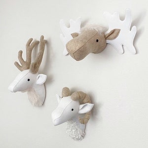 May include: Three felt animal head wall decorations. A white deer head, a white ram head with brown horns, and a brown moose head with white antlers.