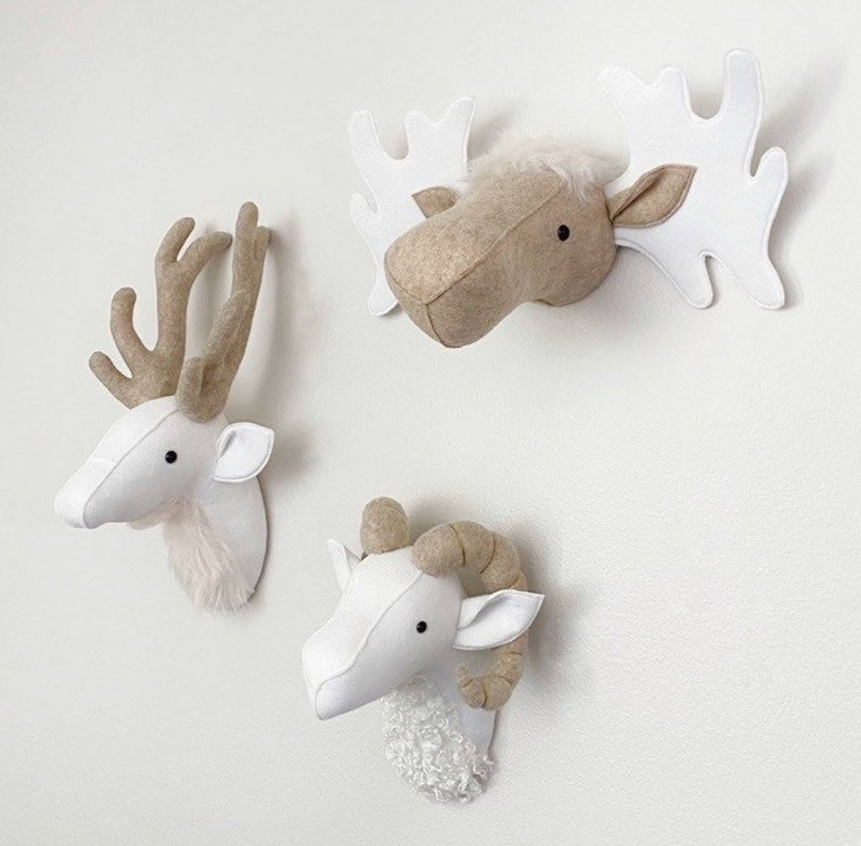 May include: Three felt animal head wall decorations. A white deer head, a white ram head with brown horns, and a brown moose head with white antlers.
