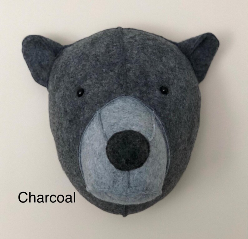 May include: A charcoal gray felt bear head wall decor with black eyes and a gray felt nose.