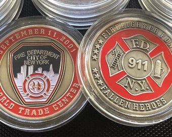 May include: Two commemorative coins in clear plastic cases. The front of the coin features a black and white image of the World Trade Center towers with the text "September 11, 2001 Fire Department City of New York World Trade Center". The back of the coin features a red and silver firefighter's cross with the text "Firefighter FDNY FD 911 NY Fallen Heroes".