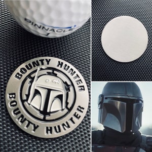Puede incluir: Un pin de metal plateado con una imagen en blanco y negro de un casco mandaloriano. El pin es redondo y tiene las palabras "BOUNTY HUNTER" escritas alrededor del borde.