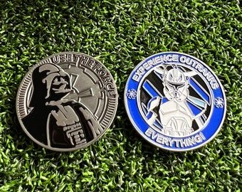 May include: Two silver metal collectible coins with a Star Wars theme. The first coin features Darth Vader with the text "Use the Force". The second coin features a clone trooper with the text "Experience Outranks Everything!"