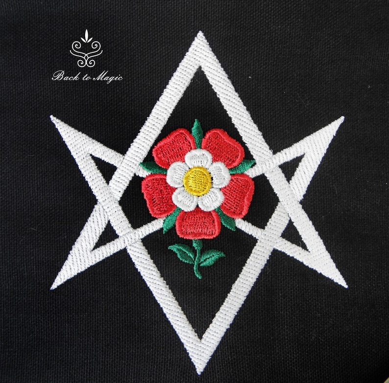 Op de afbeelding: Wit geborduurd pentagram met een rode en witte roos in het midden op een zwarte achtergrond. De tekst "Back to Magic" staat boven het pentagram.