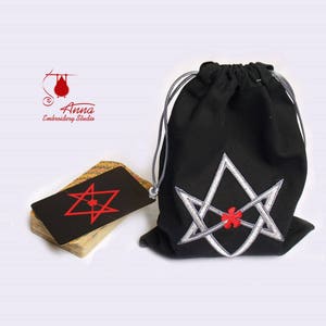May include: A black drawstring bag with a silver and red embroidered design, next to a deck of cards with a matching red star symbol. The bag and cards are likely for tarot or oracle readings. The Anna Embroidery Studio logo is in the upper left corner.
