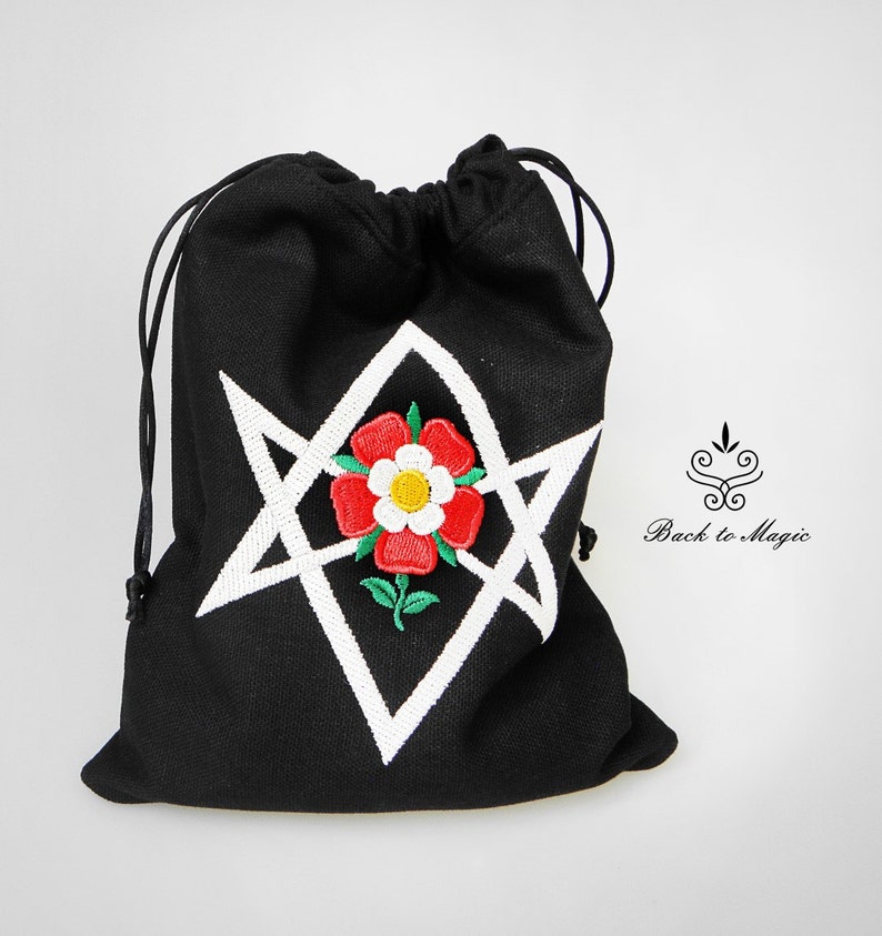Op de afbeelding: Zwarte trekkoordtas met een wit pentagram en een rode roos geborduurd op de voorkant. De tas heeft een wit trekkoord en de tekst "Back to Magic" is zichtbaar op de achtergrond.