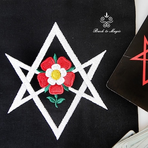 Op de afbeelding: Witte geborduurde pentagram met een rode roos in het midden op een zwarte stoffen achtergrond. De tekst "Back to Magic" is zichtbaar in de rechterbovenhoek.