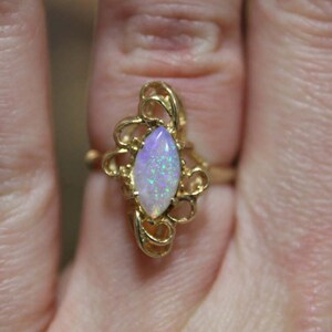 May include: A gold ring with a delicate filigree design and a white opal gemstone.