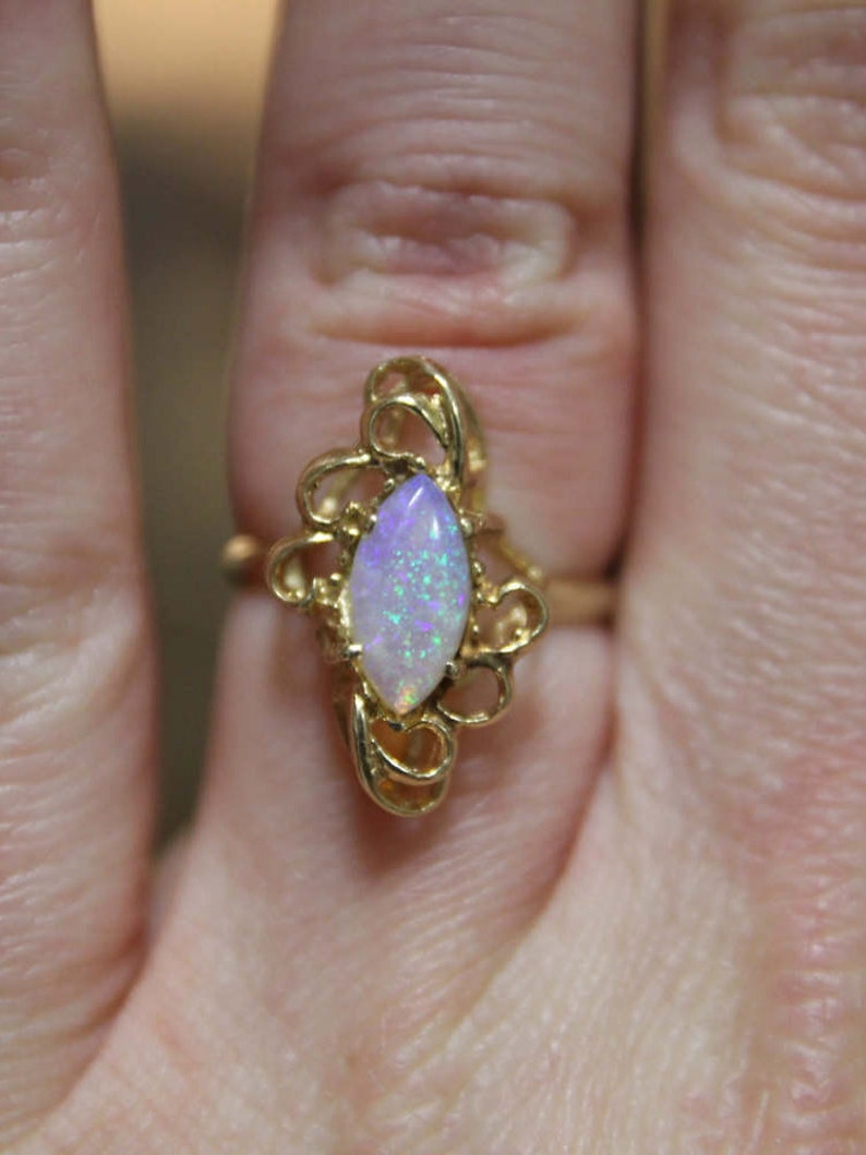 May include: A gold ring with a delicate filigree design and a white opal gemstone.