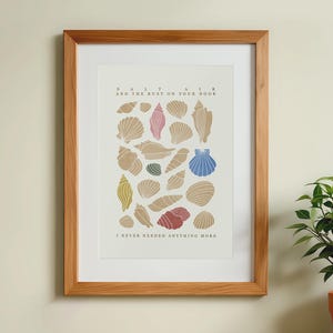May include: A framed print with a white background and a collection of seashells in various colors and shapes. The text "Salt Air and the Rust on Your Door I Never Needed Anything More" is printed below the seashells.