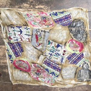 Könnte beinhalten: Ein beiger Seidenschal mit einem farbenfrohen Muster aus von amerikanischen Ureinwohnern inspirierten Designs. Der Schal zeigt geometrische Formen, Tiere und Symbole in Rot-, Blau-, Grün- und Gelbtönen.