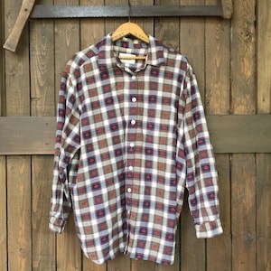 May include: A long-sleeved plaid shirt with a brown, white, blue and red plaid pattern. The shirt has a button-up front and a collar.