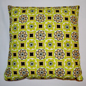 Puede incluir: Una almohada verde y amarilla con un patr&oacute;n geom&eacute;trico de flores y cuadrados.