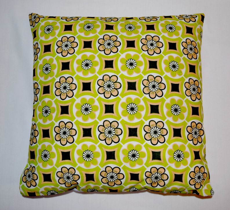 Puede incluir: Una almohada verde y amarilla con un patr&oacute;n geom&eacute;trico de flores y cuadrados.
