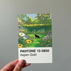 K&ouml;nnte beinhalten: Eine rechteckige Karte mit einem Gartenbild, einschlie&szlig;lich einer schwarzen Katze. Die Karte zeigt den Text "PANTONE 13-0850 Aspen Gold". Die Gartenszene zeigt Blumen, B&auml;ume und einen blauen Himmel.