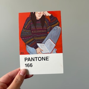 Könnte beinhalten: Ein Pantone-Farbmuster mit einem Gemälde einer Person, die ein Buch liest und einen gemusterten Pullover und blaue Jeans trägt. Das Muster ist rot mit dem Text "PANTONE 166" in Weiß.