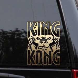 May include: Gold vinyl decal with the words "KING KONG" in black letters. The word "KING" is above the word "KONG" and a black and white gorilla face is between the words.