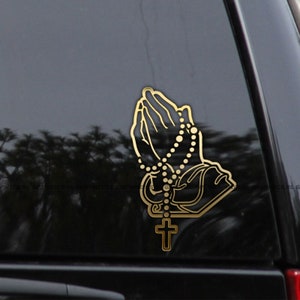 May include: Gold-colored vinyl decal of praying hands holding a rosary with a cross at the bottom.