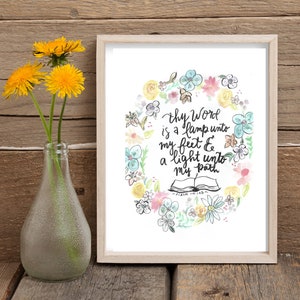 May include: A watercolor print with a floral wreath surrounding the text "Thy Word is a lamp unto my feet & a light unto my path" with the scripture reference "Psalm 119:105".