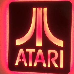 May include: A red neon sign with the Atari logo and the word "ATARI" in white.