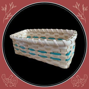 May include: Rectangular woven basket with a natural, light-colored weave and turquoise accents. The basket is made of woven strips of material and has a sturdy construction. The basket is ideal for storage or display.