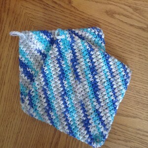 Puede incluir: Dos agarraderas de olla de ganchillo a rayas azules, blancas y azul claro con un lazo para colgar.