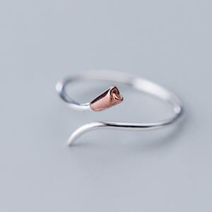 May include: A silver ring with a rose gold swirl design. The ring has a delicate, feminine look.