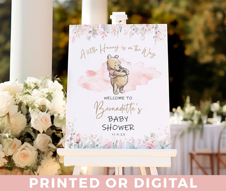 May include: A Winnie the Pooh themed baby shower welcome sign with pink and green floral accents. The sign features a watercolour background with the text "A little Hunny is on the Way" and "Welcome to Bernadette's Baby Shower 11.5.23".
