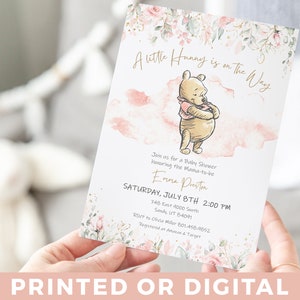 May include: A Winnie the Pooh themed baby shower invitation featuring pink and green watercolour flowers. The invitation reads "A Little Hunny is on the Way" and includes the name Emma Preston, the date and time of the shower, and the address. RSVP information and registry details are also included.