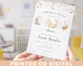 May include: A baby shower invitation with a Winnie the Pooh theme. The invitation is decorated with floral illustrations and features the text "A little honey is on the way!" and "Please join us for a baby shower".