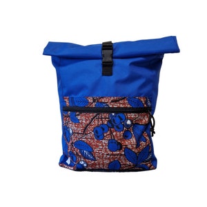May include: A blue roll-top backpack with a black buckle and a zippered pocket. The front pocket features a colorful fabric with a pattern of blue berries and leaves on a red and white background.