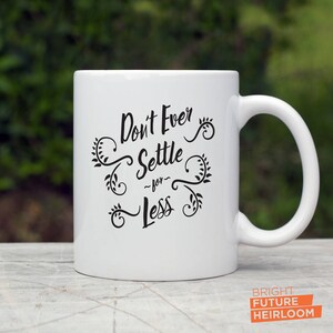 May include: White ceramic mug with black text that reads "Don't Ever Settle -for- Less" with decorative floral designs.