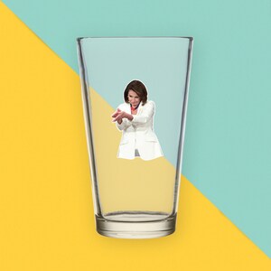 May include: A clear glass with a white sticker of a woman clapping her hands. The woman is wearing a white suit jacket and a red scarf.