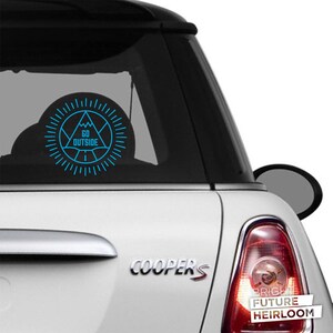 May include: A white Mini Cooper S with a blue and white sticker on the back window. The sticker features a mountain range with the text "GO OUTSIDE".
