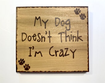May include: Wooden sign with the text "My Dog Doesn't Think I'm Crazy" and paw prints burned into the wood.