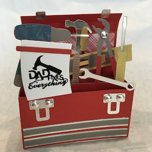 May include: A red toolbox with a pop-up design, featuring various tools and the text "DAD fixes everything".