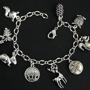May include: A silver charm bracelet with a variety of nature-themed charms, including a squirrel, owl, acorn, dragonfly, deer, and a tree.
